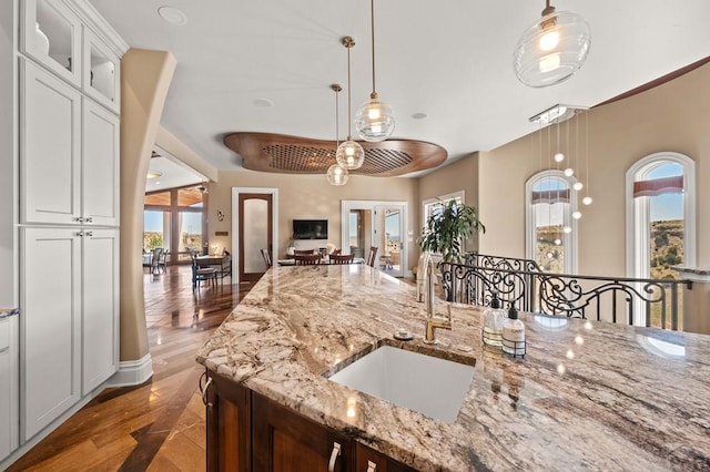 kitchen with light stone counters, glass insert cabinets, decorative light fixtures, and white cabinetry