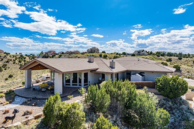 view of front of property with a tiled roof, a chimney, a patio area, and stucco siding