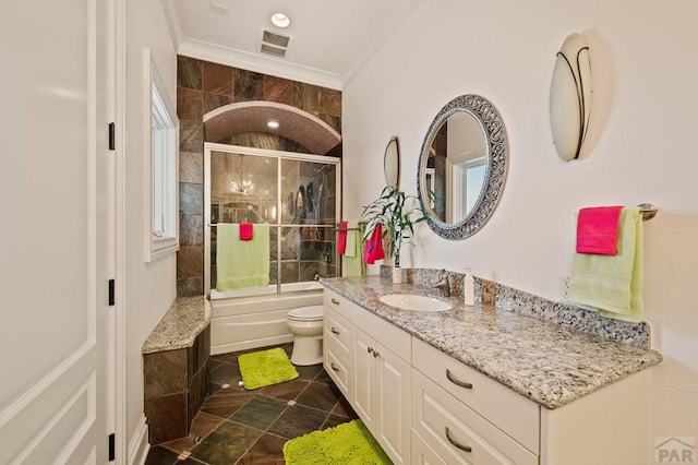 bathroom featuring toilet, bath / shower combo with glass door, visible vents, vanity, and ornamental molding