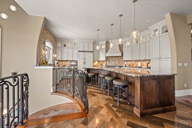 kitchen with glass insert cabinets, white cabinetry, paneled refrigerator, and light stone counters