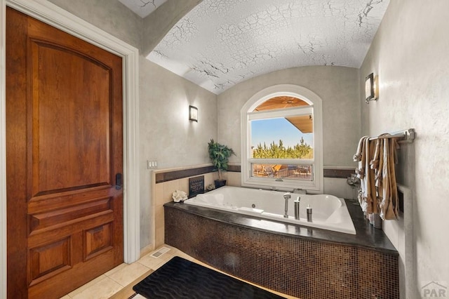 bathroom featuring lofted ceiling, a bathing tub, a textured ceiling, and tile patterned floors