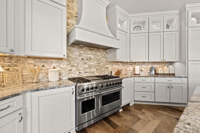 kitchen featuring range with two ovens, custom range hood, glass insert cabinets, and white cabinetry