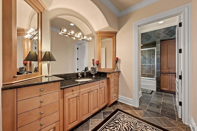 full bathroom featuring ornamental molding, a tile shower, vanity, and baseboards