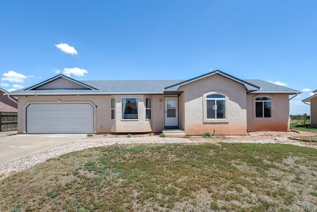 ranch-style house featuring a front yard, driveway, an attached garage, and stucco siding