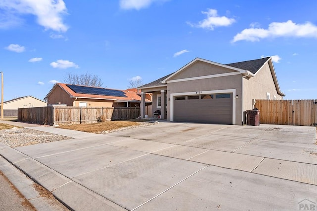 ranch-style house with a garage, concrete driveway, fence, and stucco siding