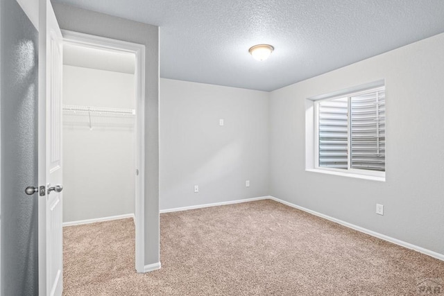 unfurnished bedroom with light carpet, a textured ceiling, a closet, and baseboards