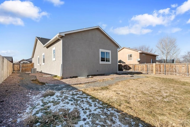 rear view of property featuring cooling unit, a fenced backyard, and stucco siding