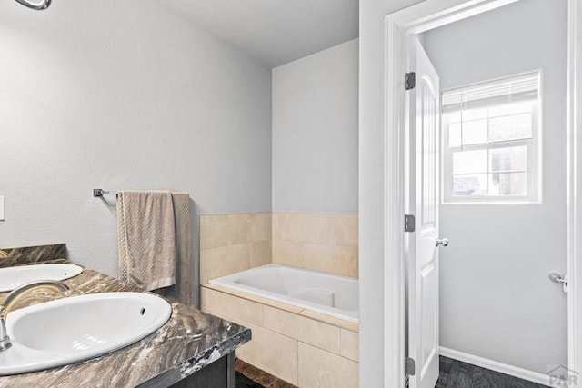 bathroom with a garden tub, double vanity, and a sink