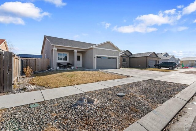 ranch-style house featuring an attached garage, fence, driveway, a residential view, and stucco siding