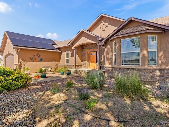 406 N Idledale Dr, Pueblo West, CO 81007 - view of front of home with stone siding, roof mounted solar panels, stucco siding, and a patio area