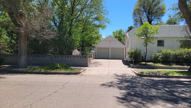 view of front of house with an outbuilding, fence, a detached garage, and stucco siding