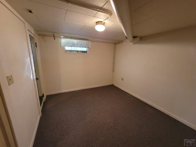 basement featuring dark colored carpet and baseboards