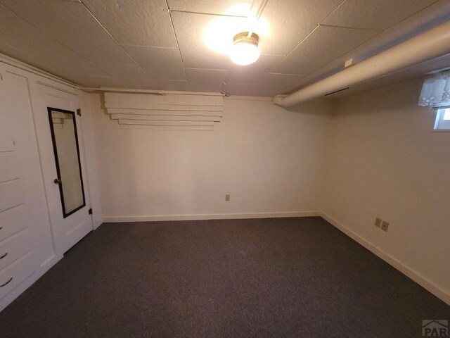 finished basement featuring baseboards and dark colored carpet