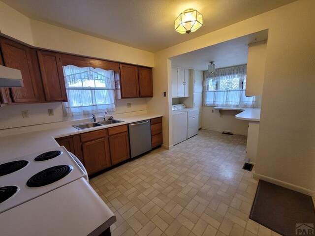 kitchen with washing machine and dryer, a sink, light countertops, stainless steel dishwasher, and brown cabinets