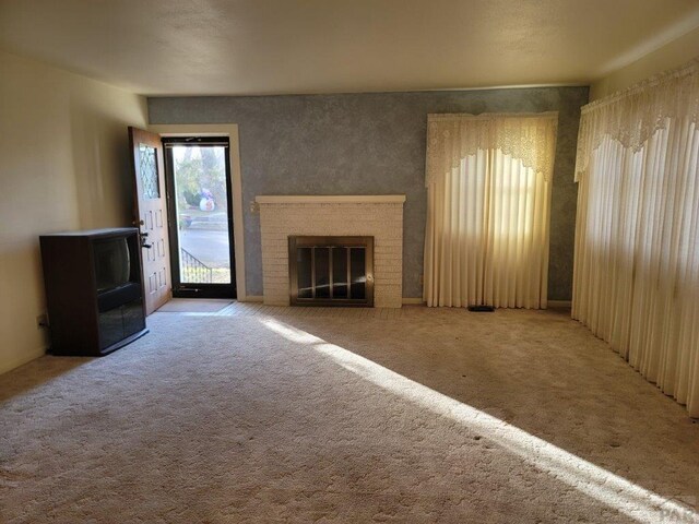 unfurnished living room with carpet floors and a brick fireplace