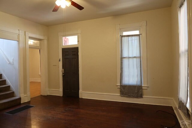 foyer with ceiling fan, dark wood-type flooring, visible vents, baseboards, and stairs