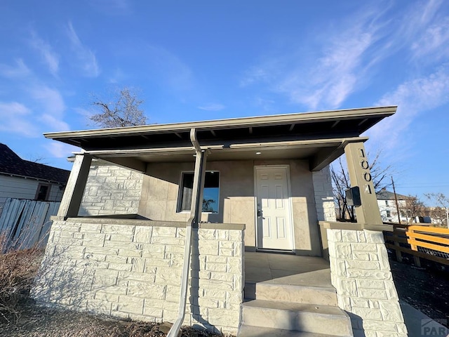 view of front facade featuring fence, covered porch, and stucco siding