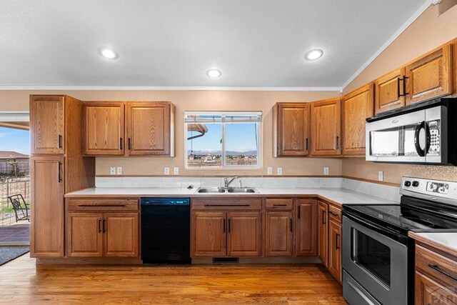 503 N Iliff Dr, Pueblo West, CO 81007 - kitchen featuring stainless steel appliances, a sink, crown molding, brown cabinets, and plenty of natural light