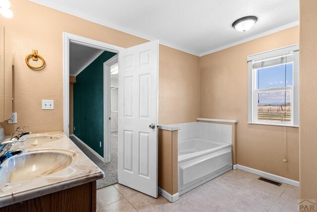 503 N Iliff Dr, Pueblo West, CO 81007 - bathroom featuring a garden tub, baseboards, tile patterned floors, crown molding, and double vanity