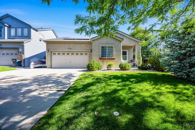 3721 Bison Ln, Pueblo, CO 81005 - view of front of property with stucco siding, concrete driveway, solar panels, a front yard, and a garage