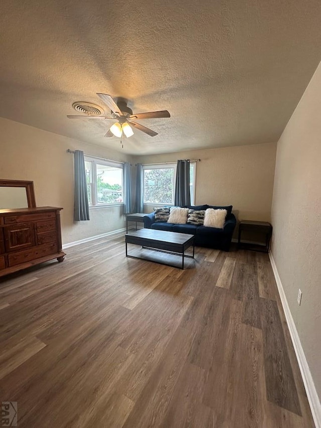 bedroom featuring visible vents, baseboards, ceiling fan, wood finished floors, and a textured ceiling