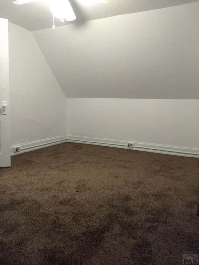 bonus room featuring vaulted ceiling, dark carpet, a ceiling fan, and baseboards