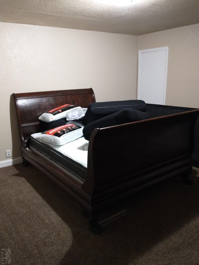 bedroom with a textured ceiling, baseboards, and carpet flooring