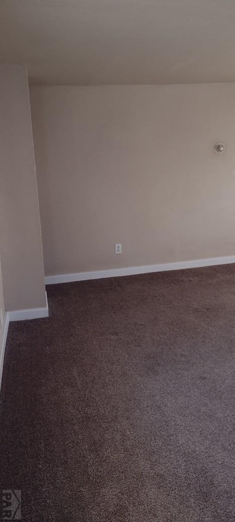 spare room featuring baseboards and dark colored carpet