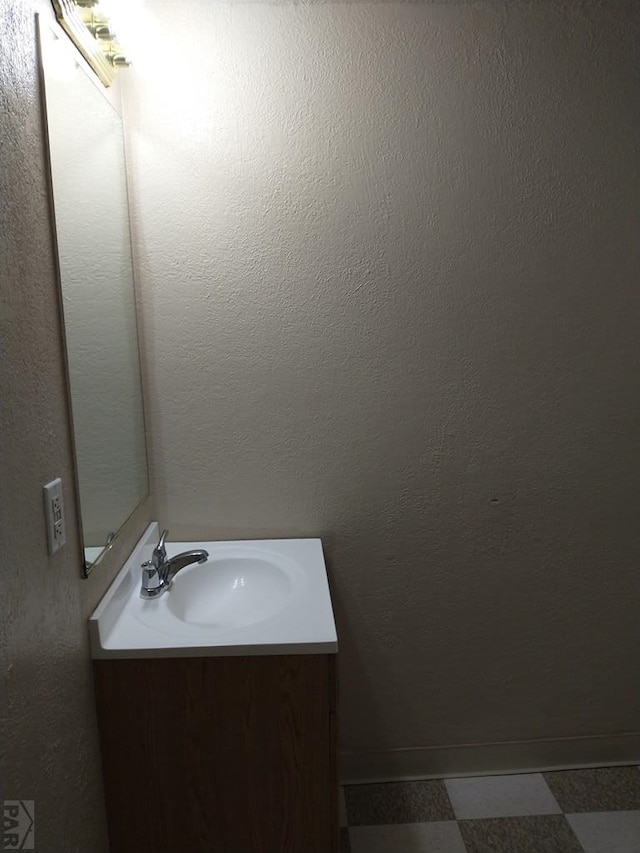 bathroom with tile patterned floors, a textured wall, and vanity