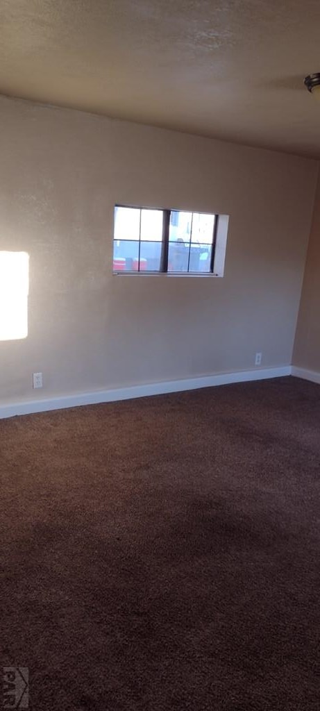 empty room featuring carpet floors, a textured ceiling, and baseboards