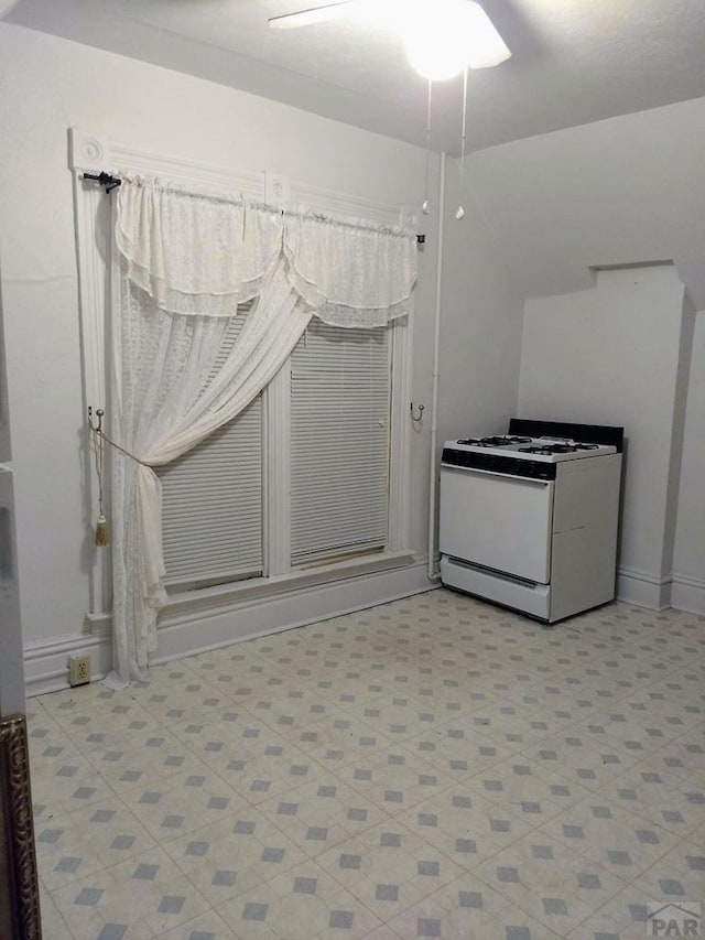 kitchen with baseboards, light floors, and white gas range oven