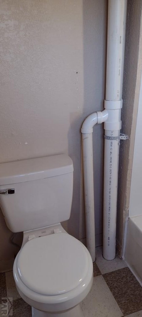 full bath featuring a bathtub, toilet, and tile patterned floors