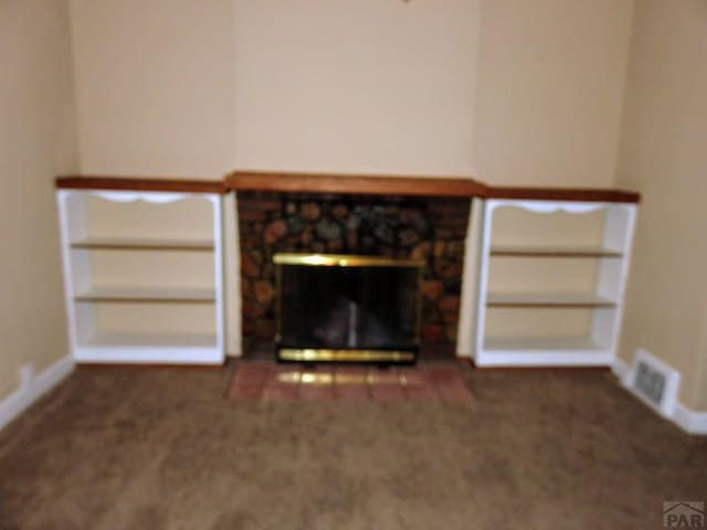 unfurnished living room featuring baseboards, visible vents, dark colored carpet, and a stone fireplace