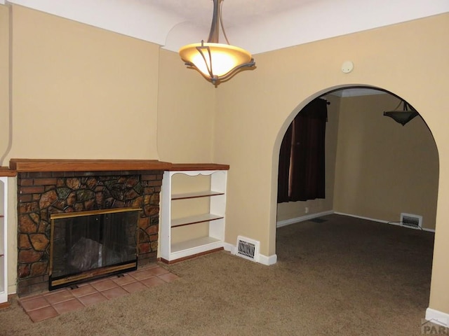 unfurnished living room with arched walkways, a stone fireplace, carpet, and visible vents