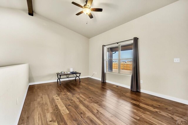 spare room with vaulted ceiling with beams, ceiling fan, baseboards, and dark wood finished floors