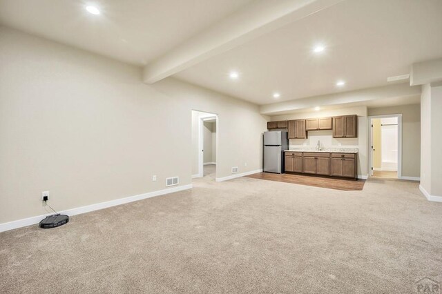 unfurnished living room with recessed lighting, light carpet, a sink, visible vents, and beamed ceiling