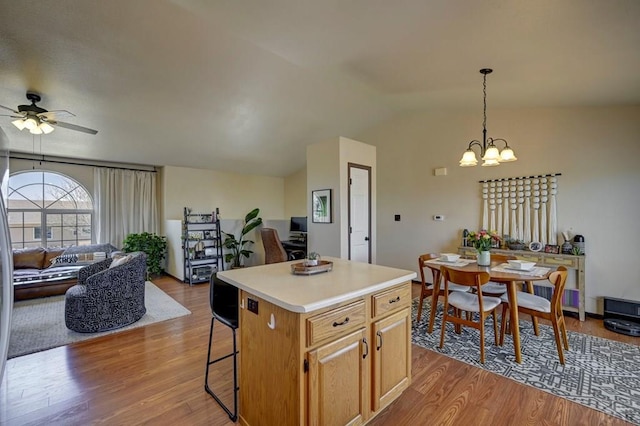 769 S Mccoy Dr, Pueblo West, CO 81007 - kitchen with ceiling fan with notable chandelier, a breakfast bar, a center island, wood finished floors, and open floor plan