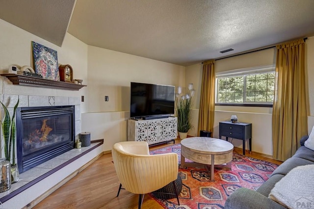 769 S Mccoy Dr, Pueblo West, CO 81007 - living area with a tiled fireplace, visible vents, a textured ceiling, and wood finished floors