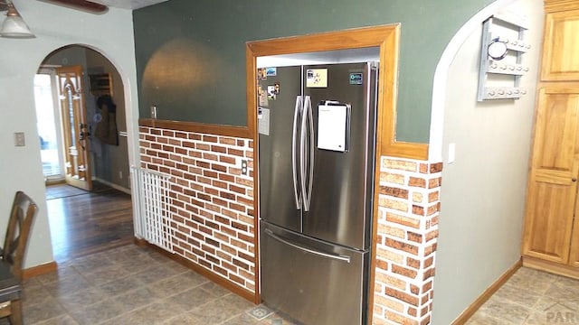 kitchen featuring baseboards, arched walkways, and freestanding refrigerator