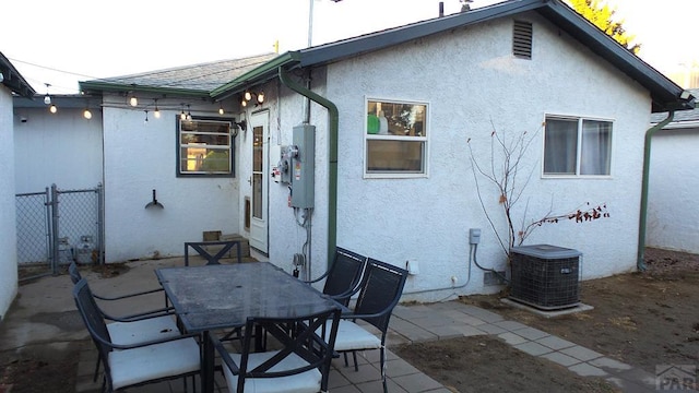 back of property with roof with shingles, central air condition unit, stucco siding, outdoor dining space, and a patio area