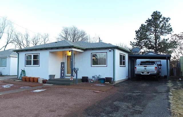 view of front of house with a shingled roof, aphalt driveway, and stucco siding