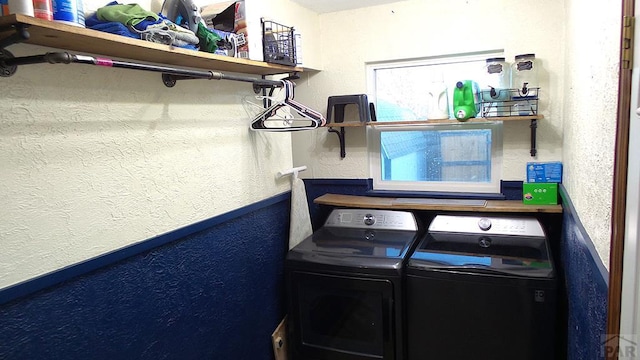 laundry room with a textured wall, laundry area, and washer and clothes dryer