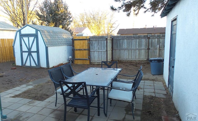 view of patio featuring a storage shed, outdoor dining area, an outbuilding, and a fenced backyard