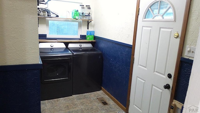 laundry room featuring a textured wall, laundry area, visible vents, washer and clothes dryer, and plenty of natural light