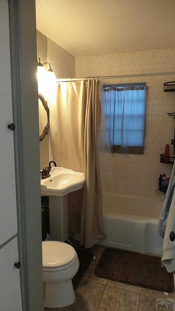 bathroom with a sink, tile patterned flooring, toilet, and shower / bathtub combination with curtain