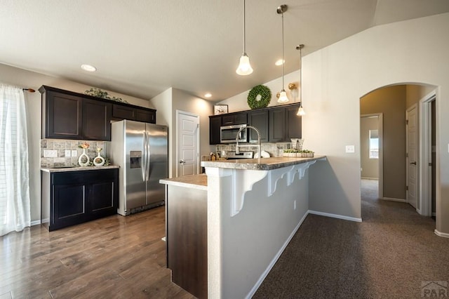 kitchen featuring a breakfast bar, pendant lighting, arched walkways, stainless steel appliances, and a peninsula