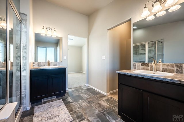 full bathroom with a stall shower, two vanities, a sink, and baseboards