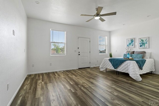 unfurnished bedroom featuring dark wood-type flooring, multiple windows, and baseboards