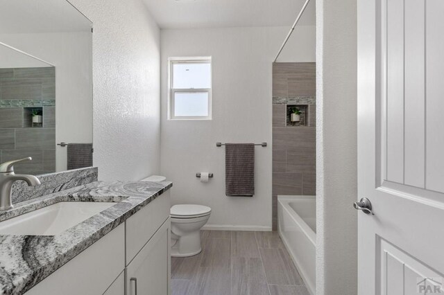 full bathroom with toilet, shower / tub combination, baseboards, and vanity