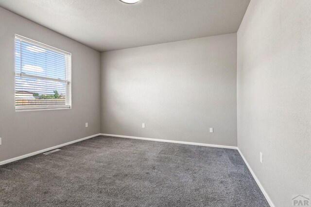 unfurnished room with carpet floors, visible vents, and baseboards